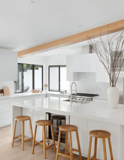 A white kitchen with wooden floors and stools.